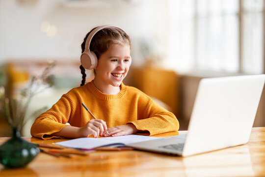 Happy girl having online lesson via laptop at home