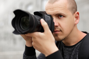 close up portrait of male photographer taking photo with modern dslr camera
