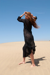 Muslim woman in a black robe in the desert dunes