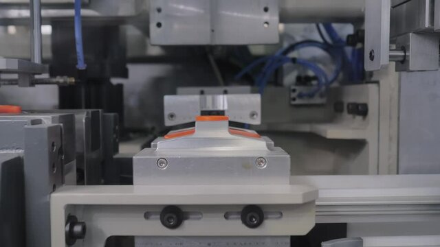 Production line of automatic blow molding machine - forming empty orange plastic jerrycans on conveyor belt with hydraulic punch- close up. Manufacturing, industry, technology equipment concept