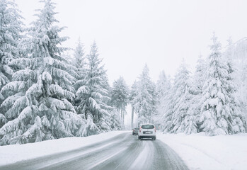 Fototapeta premium Cars keep their distance on the snow-covered road.Family trip, vacation, adventure. Winter landscape. Driving a car in extreme winter conditions.Travel concept background