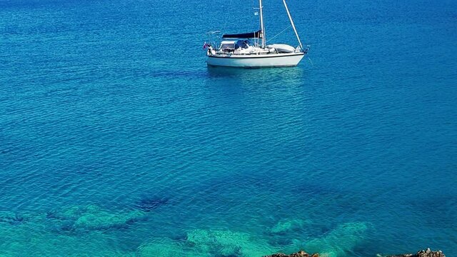 Blue and turquoise sea of the Aegean and white sailing boat, Greece