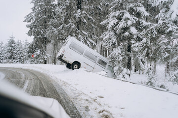 An accident on a winter snow-covered highway with a car skidding and falling into a ditch due to...