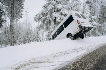 An accident on a winter snow-covered highway with a car skidding and falling into a ditch due to...