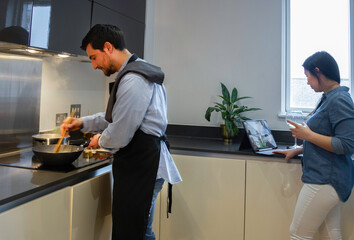 man cooking with her girlfriend chatting on the tablet