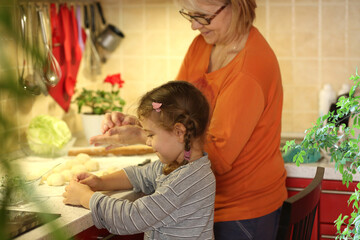 Grandmother and granddaughter are cooking together. The family cooks together in the kitchen. Traditions. Healthy food concept.