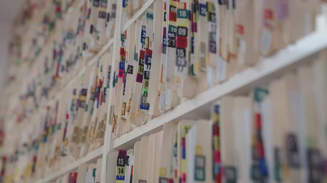 Medical cards on shelves in hospital. Health insurance folders in archive files. Records and catalogs in medicine clinic. Patient healthcare information