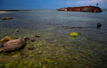 shipwreck in the sea with polluted water and storm clouds 