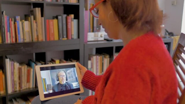 Mujer adula con gafas realiza videoconferencia con su marido con mascarilla y aud&iacute;fonos