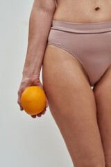 Hand carrying an orange near a hip