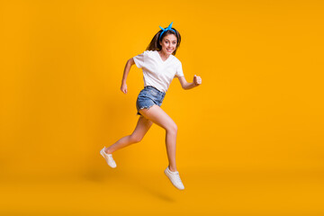 Fototapeta na wymiar Full length body size photo of girl running fast jumping high hurrying up isolated on vivid yellow color background