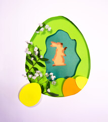 Design for the holiday Happy Easter. Paper art. Egg and rabbit shape cut from paper. Framed with natural plants. For your Easter background. Copy space and flat lay style