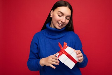 Photo of beautiful positive smiling young brunette woman isolated over red background wall wearing...