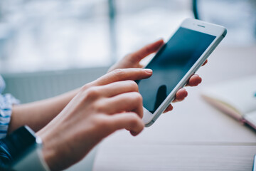 Crop faceless woman using tablet in light room