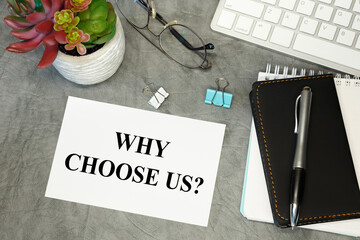 Why choose us - lettering on paper on the desktop, notepad, pen and keyboard.