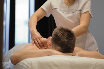 Close-up of man enjoying in relaxing shoulders massage . Man relaxing on massage table receiving massage