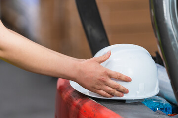 Closeup shot of a hand picking up a white hard hat
