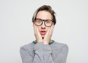 Portrait of insecure and scared handsome young man, wear glasses hold hands pressed to chest