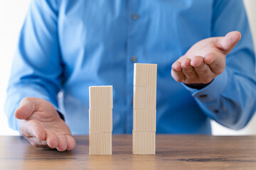 Businessman hand arranging wooden blocks in an upward stepping stair.  Concept for growth, success, investment strategy.