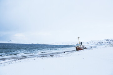 old rusty ship on the coast of the arctic ocean in winter.  