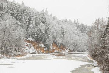 Velnalas klintis un Velna ala Devil’s rock and Devil’s cave Sigulda Latvia winter wonderland snow covered Gauja river national park frozen sandstone cliffs 