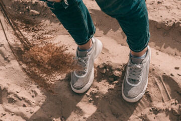 a girl in gray sneakers stands on the sand