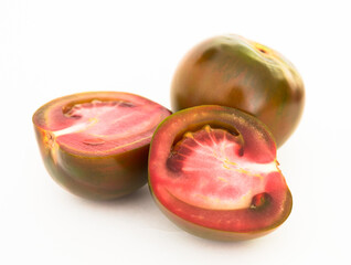 black tomatoes and two halves on white background