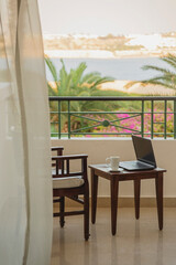 Freelancer or businessman working remotely with laptop on hotel balcony at resort while traveling. Workplace without people