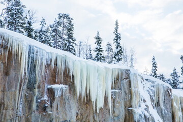 icicles hang from a cliff with trees