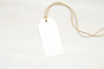 Empty plain rectangle tag mockup on white wooden background for design presentation.