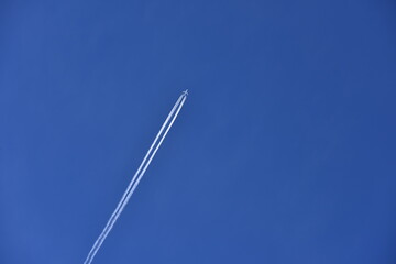 Blue sky with white airplane long contrail.Blue sky happy vacation time for freezing. large free area.