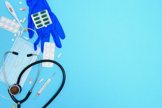 Top view of medicines, work tools and accessories doctor, nurse. Medical set - Tablets, thermometer, syringe, ampoules, adhesive plaster and statoscope on a blue background. Flat lay