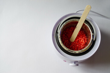 depilation wax heater with melted wax inside and wooden stick on white background
