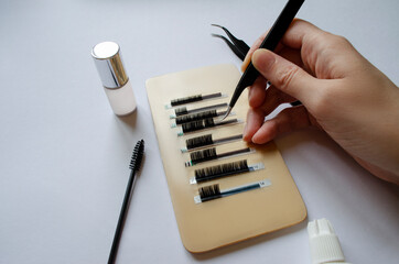 eyelash extension concept. hand with eyelash extension tweezers removes eyelashes from the tape