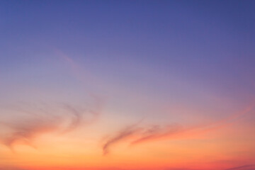 Colorful sunset sky in the evening on twilight with peaceful orange sunlight cloud fluffy and dark blue dusk sky background. 