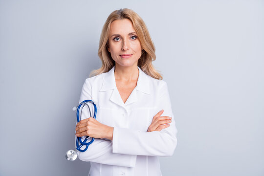 Photo of mature serious professional woman doctor with crossed hands hold stethoscope isolated on grey color background