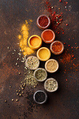 Set of various colorful spices in jars over dark brown concrete background. Assorted condiment. Top...