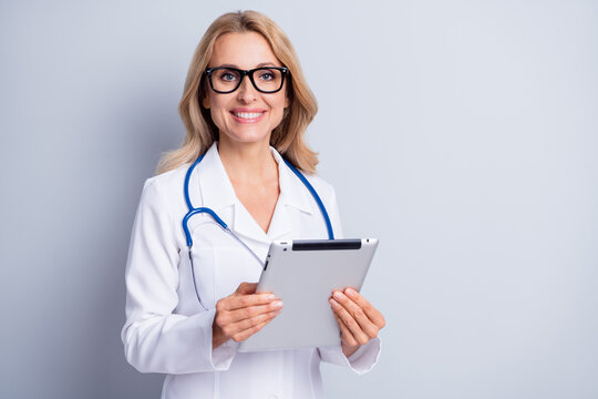 Photo of mature happy smiling doctor woman in glasses hold tablet consultation isolated on grey color background