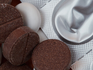 White medical pills and pills spilling out of a medicine bottle. A top-down macro with space to copy.