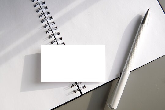 Business card mockup, small blank paper card on open notebook for design presentation.