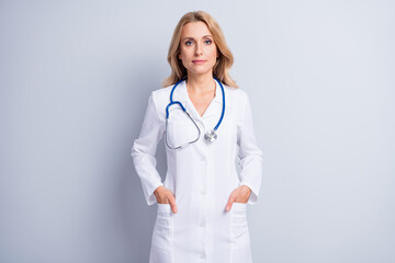 Photo of charming person put hands in pockets stethoscope hang on neck isolated on grey color...