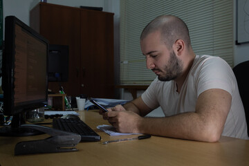 Hombre calvo escribe por teléfono móvil en oficina serio