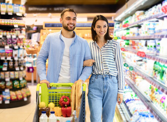 Cheerful couple with the cart shopping in supermarket