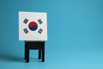 National flag of South Korea on a black chair, light blue background. Communication and dialog concept.