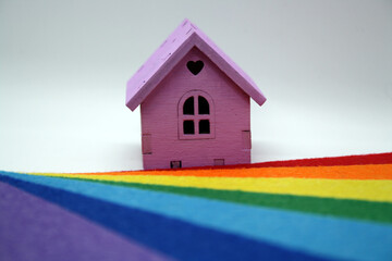 A toy wooden house on a rainbow background.