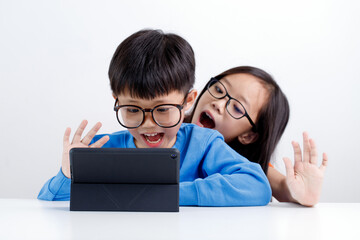 Cute little Asian sibling using tablet doing a video call with family and friend at home during the pandemic lockdown.