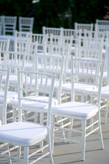 Cozy rustic wedding ceremony with white Chiavari chairs in the lawn