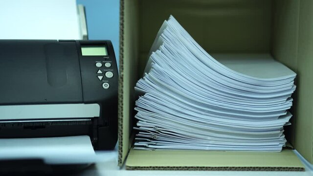 Hand of man put files document into the brown box located near the scanner.
