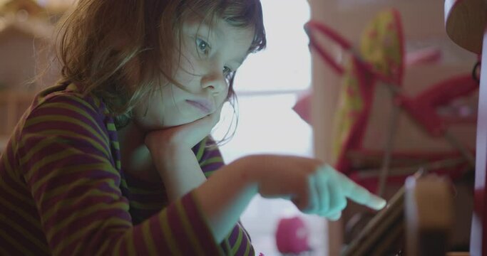 Pre-school girl is lying on the floor in her room and looking something on tablet