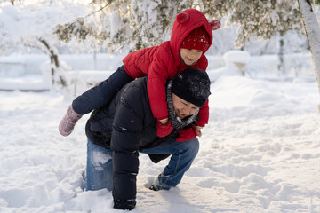 Fototapeta na wymiar Handsome young dad and his little cute daughter are having fun outdoor in winter. Enjoying spending time together. Family concept.